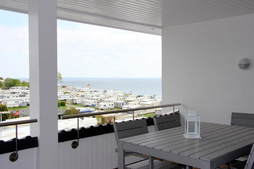 Ferienwohnung Südstrand III, überdachter Balkon mit Esstisch und Blick über den Campingplatz zur Ostsee
